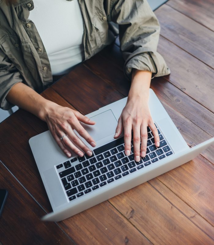 Young woman working on laptop. Freelancer at remote work. Female student learning on-line via computer. Blogger or journalist writing new article.
